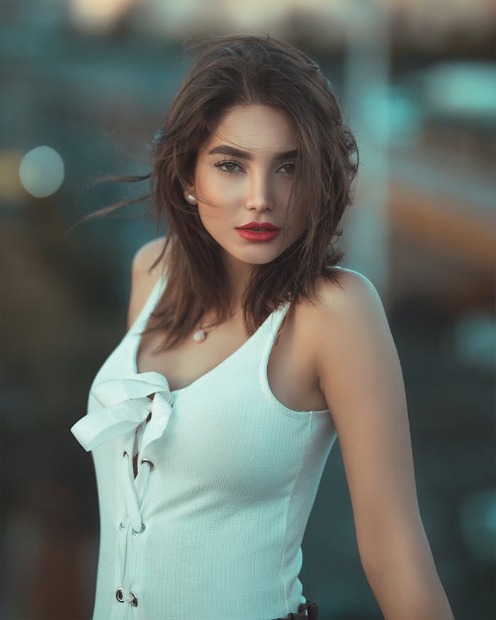 who-we-are Stunning outdoor portrait of a brunette fashion model with red lips in a stylish white outfit.