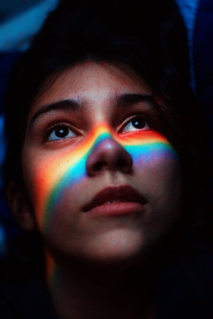embark Portrait of a woman with a rainbow light across her face, capturing a moody and artistic feel.